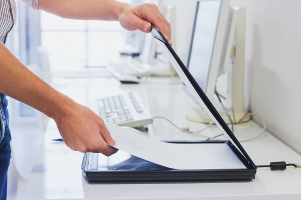 a person inserting a sheet of paper into a scanner