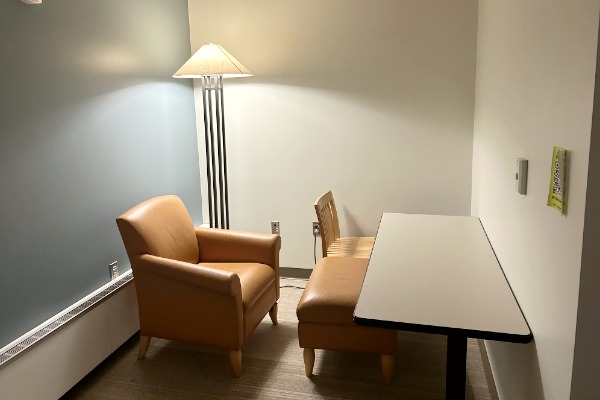 Quality of Life room. Showing an arm chair, ottoman, wood chair and table.