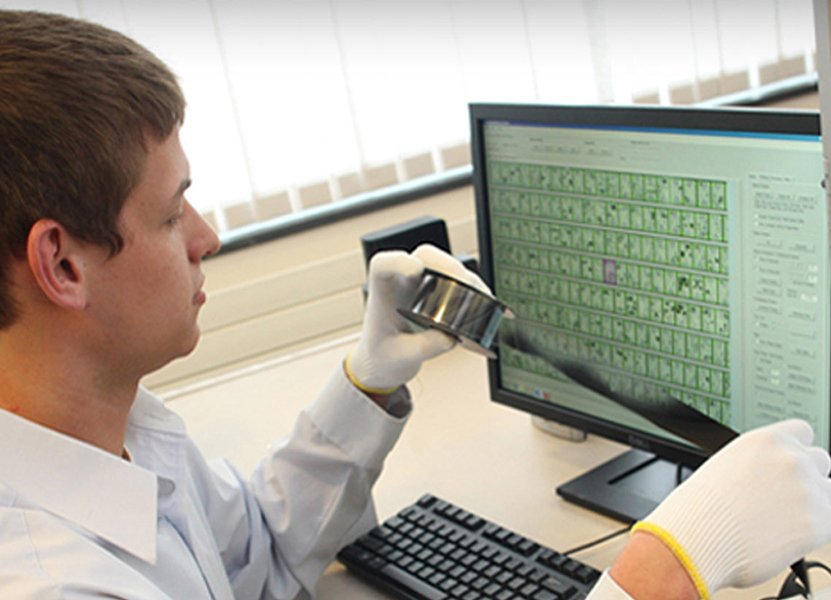 a man in a white buttoned shirt looking at a computer screen and microfilm