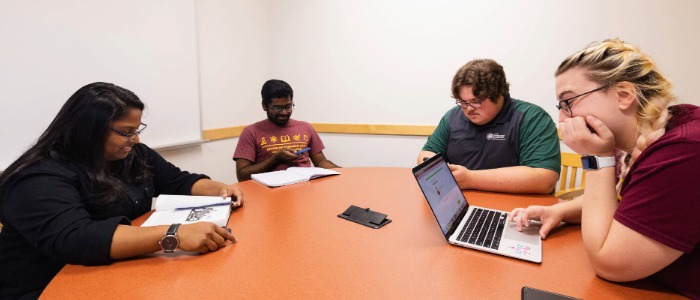 700x300 Group Study Four students are studying at a round table inside a group study room.