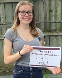 AGheadshot Image_200x250 a smiling woman holding a sign that says, Thank you. Because of your gift, I can learn and grow