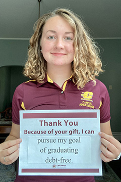 Library Scholarship Recipient Alyse March holding a sign that reads 