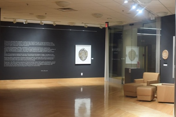 a room with a dark wall and a picture on the wall. Also armchairs on the right.