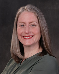 Gina McGovern portrait showing head and shoulders, smiling, on a gray background
