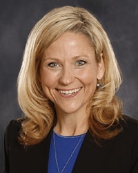 Holly Hoffman portrait showing head and shoulders, smiling, on a gray background
