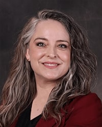 Johanna Paas portrait showing head and shoulders, smiling, on a gray background