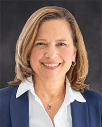 Pamela Sickinger portrait showing head and shoulders, smiling, on a gray background