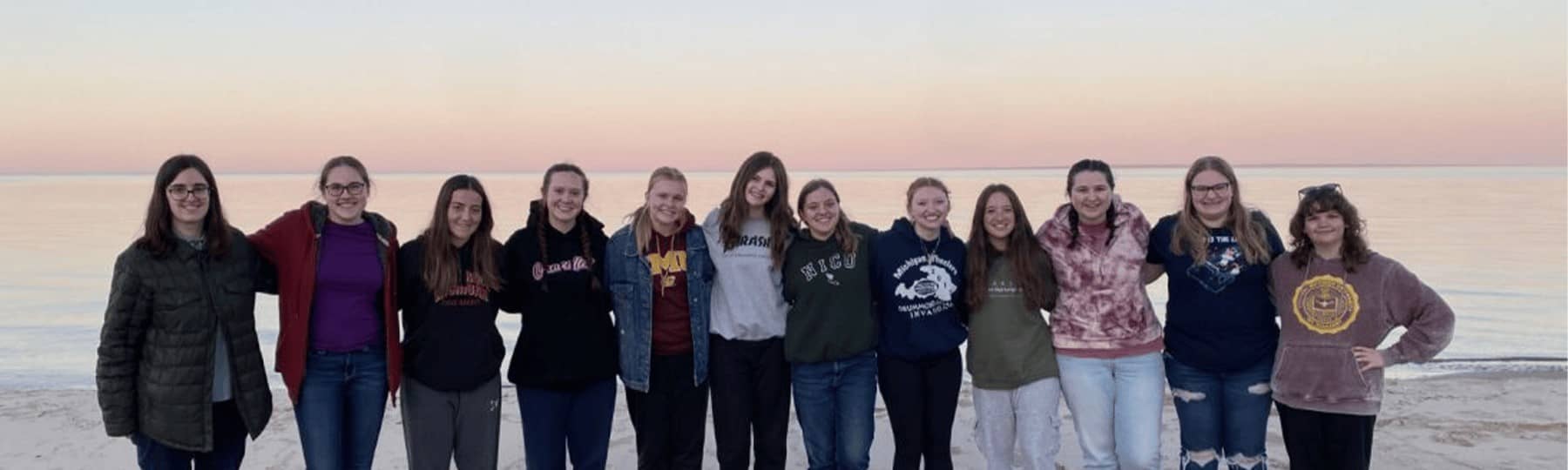 A group of women standing together on a beach.