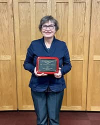 a woman in a blue suit holding a plaque and smiling