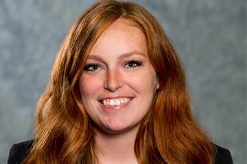 A woman in a black blazer smiling for a picture.