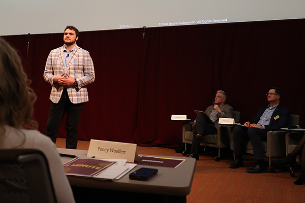 Photo of a student standing in front of a crowd presenting in French Auditorium