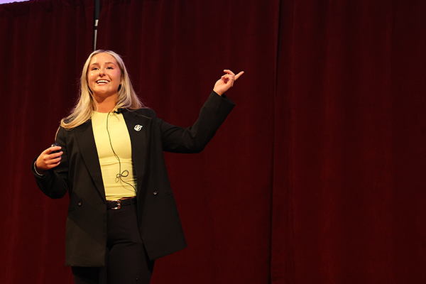 Photo of a student pitching her idea on stage and pointing