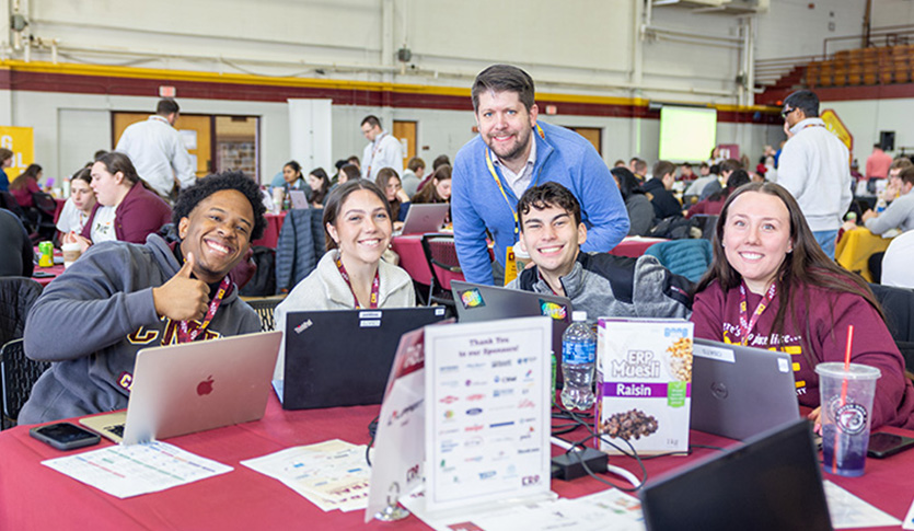 A group of people sitting at a table with laptops inside Finch Fieldhouse