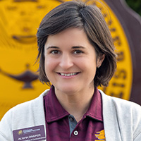 Alisha_Draper_200x200 Alisha Draper smiling in a professional headshot, wearing a maroon polo and light cardigan with the CMU seal in the background.