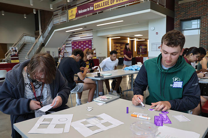 High school students work together in groups on camp projects in the Grawn Atrium