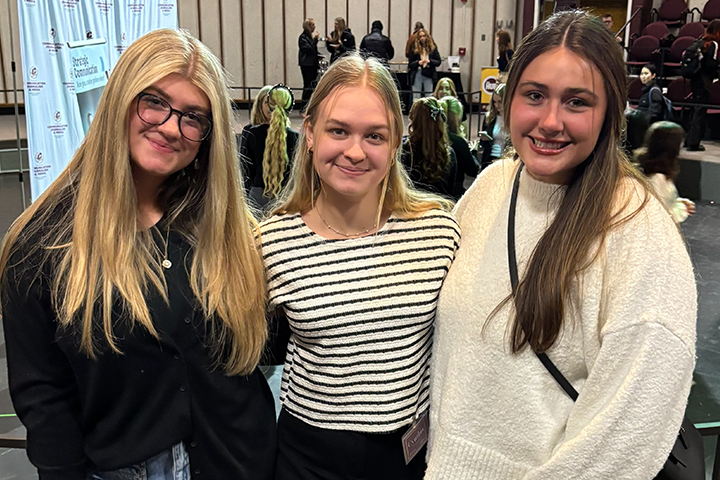 Society of Women in Business members Kennedy Burns, Cynthia Kovalcik (president), and Carmella Cortes (vice president) stand with arms around each other at an SWB event.