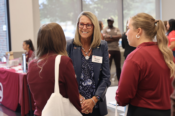 Melanie Kalmar speaks with two students during a networking event at CMU's College of Business.