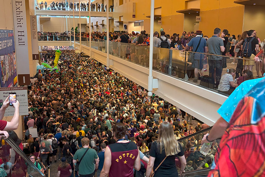 Thousands of attendees crowd the Indianapolis Convention Center for Gen Con 2025. There are people on ground level, on the stairs and on the second level. There is no free standing room.