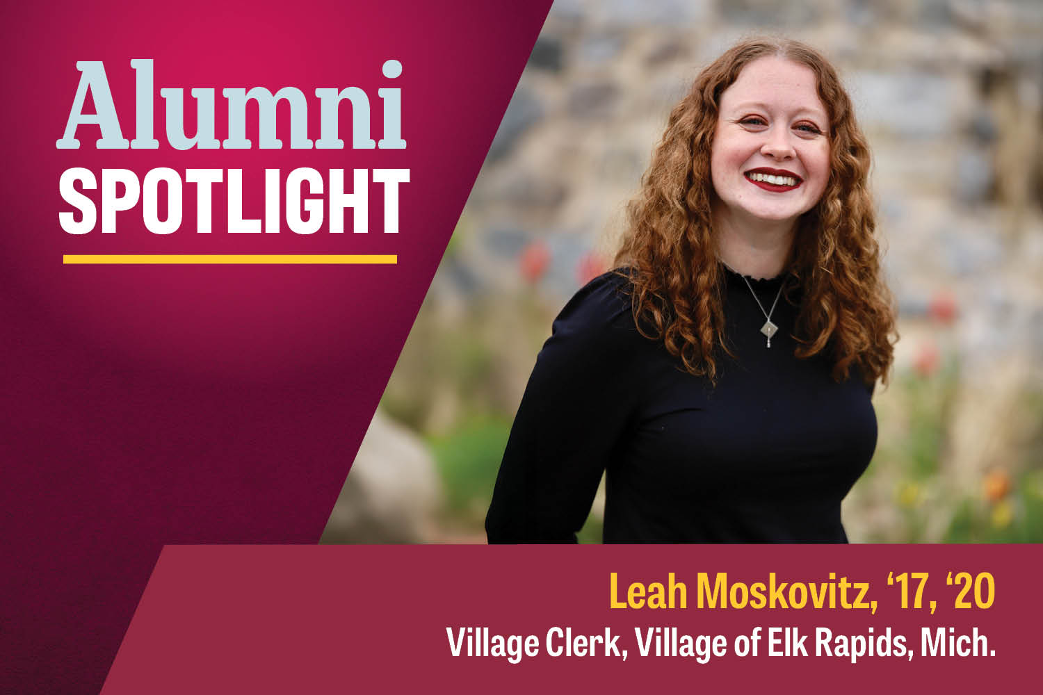 MBA alumna Leah Moskovitz has long curly red hair, wears a black long-sleeve shirt and silver necklace and poses in front of a background of blurred flowers.