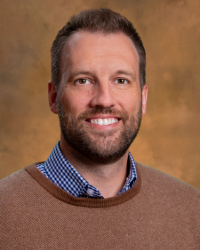 a man with a beard and mustache wearing a brown sweater