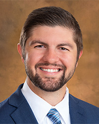 A bearded man smiling in a blue suit and tie.