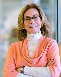 Tina Thompson, Ph.D., wearing glasses, a white sweater, and an apricot-colored wrap as she smiles at the camera.