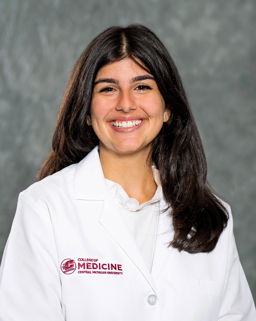 A female CMU College of Medicine medical student wearing her white coat as she smiles for the camera.