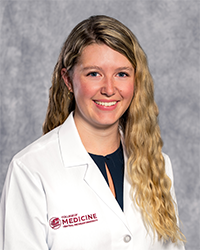 Young, Isabel 200 x 250 A female medical student in a white lab coat embroidered with a Central Michigan University College of Medicine logo.