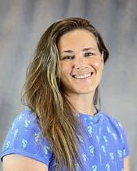 Headshot for Catherine Barrington wearing a blue shirt with green seahorses.