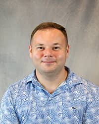 Headshot for Keith Bouffard wearing a blue print shirt.