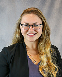 Headshot for Justin Czajka wearing a black blazer and blue top.