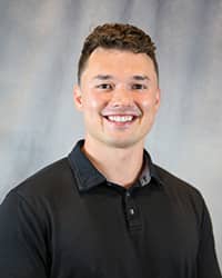 Headshot for Tanner Hewitt wearing a black polo shirt.
