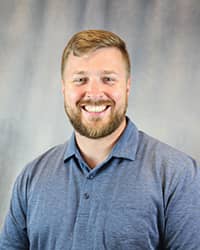 Headshot of Alex Schlangen wearing a blue polo shirt.