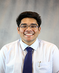 Headshot of Sachin Singh wearing a white shirt and a blue tie.