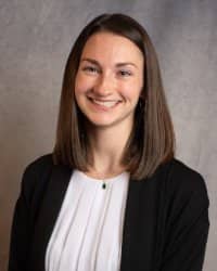 A smiling woman with medium length brown hair wearing a dark suit with a white blouse.