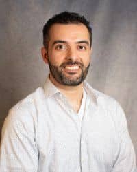 A man with a beard and white button down shirt.
