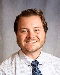 Brennon Eudis is wearing a white polka dot shirt and blue patterned tie.