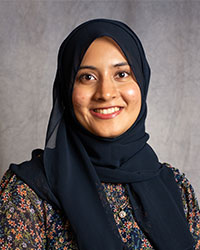 Aateqa Hashmi is wearing a floral blouse and headscarf