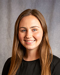 Natalie Kosnik is wearing a black blouse and has long brown hair.