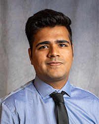 Jasvant Kumar is wearing a blue button down shirt with a black tie.