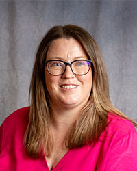 Meghan Mulqueen is wearing a pink blouse and glasses.