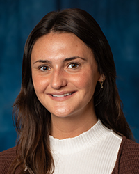 a woman with brown hair and a white turtleneck