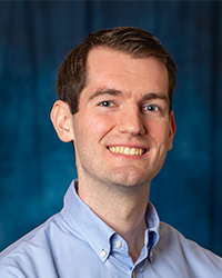 a man smiling, with a blue button down shirt