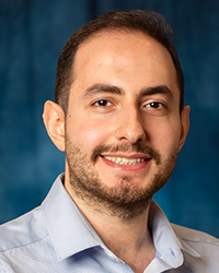 a man smiling, wearing a blue button up shirt