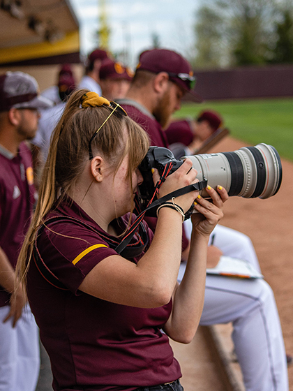 Student photographer taking pictures at a CMU baseball game