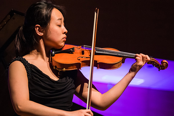 Student in formal wear, on stage, playing the violin