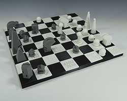 Black and white 3D printed chess board with gender specific terms etched into some of the squares on the board.