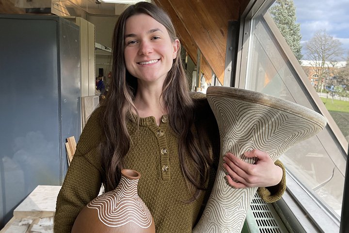 A picture of CMU student Melissa Navarre holding two ceramic percussion instruments she created