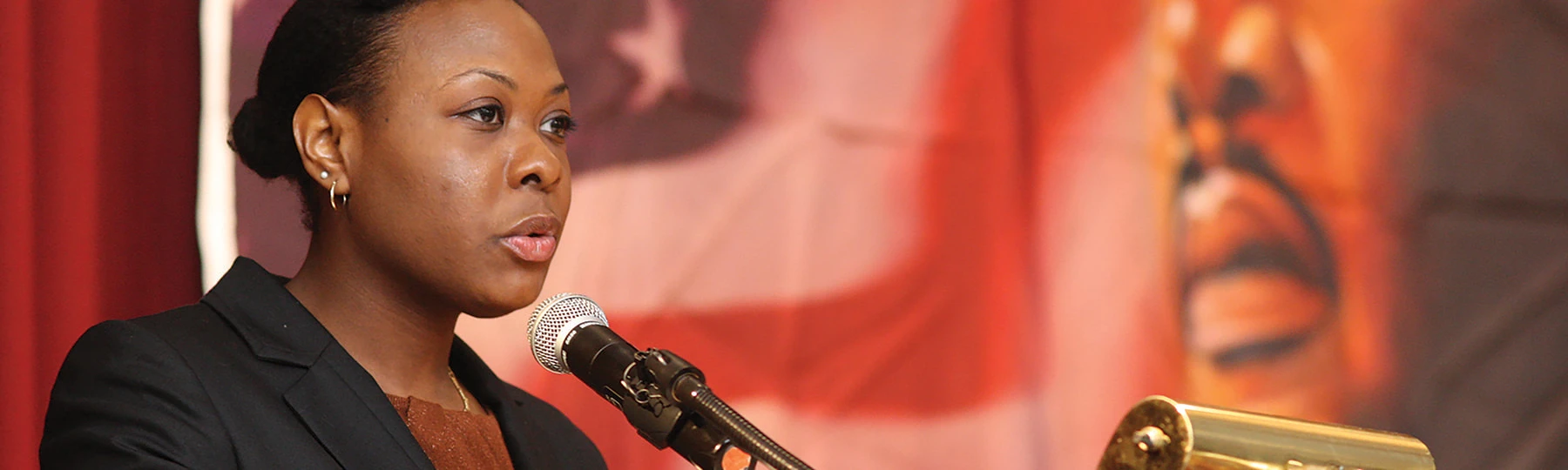 Student speaking at a podium with MLK jr. in the background.
