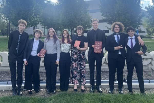 A group of people posing outside with awards.